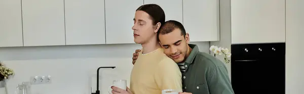 Due giovani uomini condividono un momento di intimità nella loro moderna cucina appartamento. — Foto stock