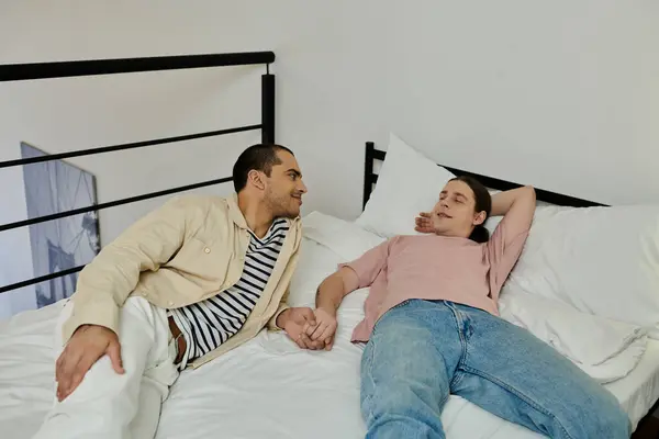 A young gay couple shares a comfortable moment together on a bed in a modern apartment. — Stock Photo