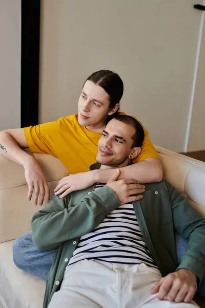 A young gay couple relaxes on a couch in their modern apartment. — Stock Photo