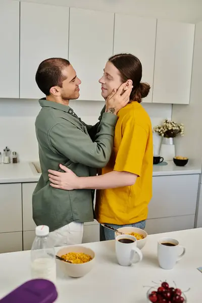 A young gay couple shares a tender moment in their modern kitchen, their casual attire and relaxed posture suggesting a cozy, intimate atmosphere. — Stock Photo