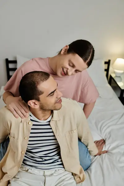 A young gay couple shows affection while relaxing on a bed in their modern apartment. — Stock Photo