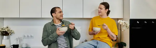 A young gay couple enjoys a casual breakfast together in their modern apartment. — Stock Photo