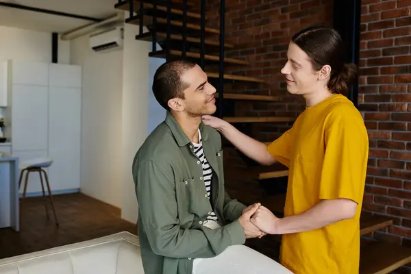 A young gay couple share a tender moment in their modern apartment, radiating love and connection. — Stock Photo