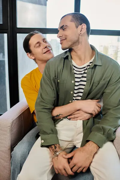 A young gay couple embraces in a modern apartment, showcasing their love and affection. — Stock Photo