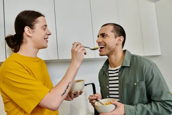 Una joven pareja gay disfruta de un desayuno informal en su apartamento moderno. - foto de stock