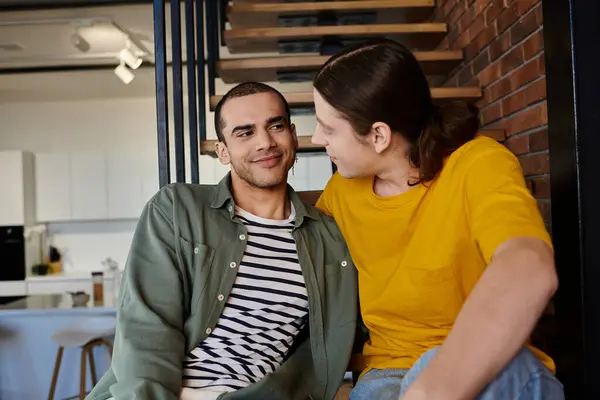A young gay couple, casually dressed, share a tender moment in their modern apartment. — Stock Photo