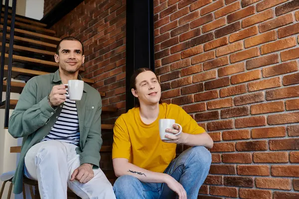 Deux jeunes hommes profitent d'une matinée détendue ensemble dans leur appartement moderne. — Photo de stock