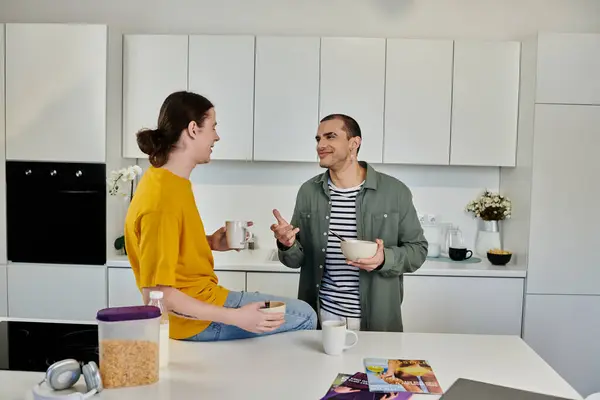A young gay couple enjoys a casual morning in their modern apartment, sharing a cup of coffee and a bowl of cereal. — Stock Photo