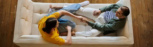 A young gay couple relaxes on a white couch in their modern apartment, enjoying a moment of intimacy. — Stock Photo