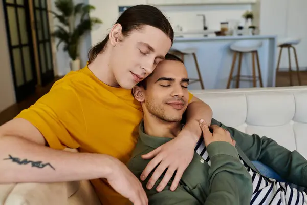 A young gay couple relaxes on a white sofa in their contemporary apartment, showcasing their love and connection. — Stock Photo