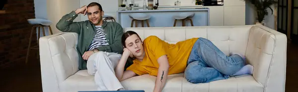 A young gay couple relaxes on a white sofa in their modern apartment, enjoying a moment of peace and togetherness. — Stock Photo
