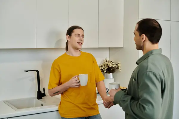 A young gay couple enjoys a cozy morning together in their modern apartment, sharing a cup of coffee and a warm conversation. — Stock Photo
