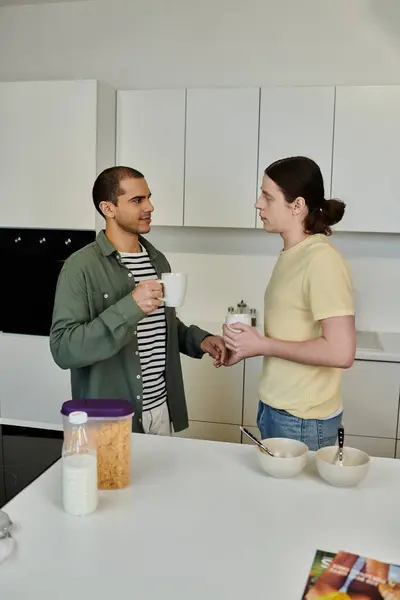A young gay couple enjoys a relaxed morning together in their modern apartment, sharing a cup of coffee and a light breakfast. — Stock Photo