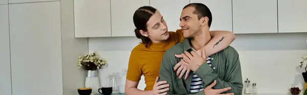 A young gay couple shares a tender moment of affection in their modern apartment kitchen. — Stock Photo