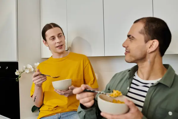 A young gay couple enjoys a casual breakfast of cereal in their modern apartment. — Stock Photo