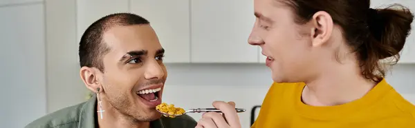 A young gay couple enjoys a breakfast of cereal together in their modern apartment. — Stock Photo