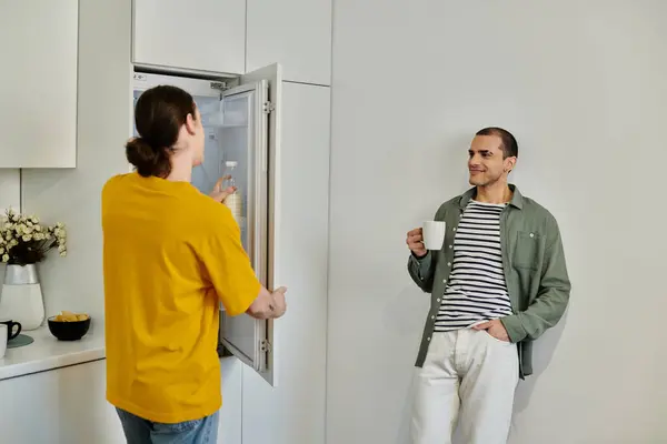 A young gay couple in casual attire enjoys a quiet morning in their modern apartment. — Stock Photo