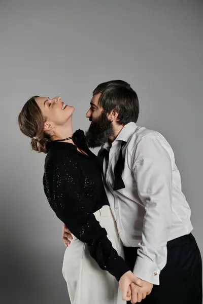 A loving couple, dressed in sophisticated attire, pose together against a grey backdrop. — Stock Photo