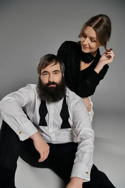 A man and woman dressed in formal attire pose against a gray backdrop. — Stock Photo