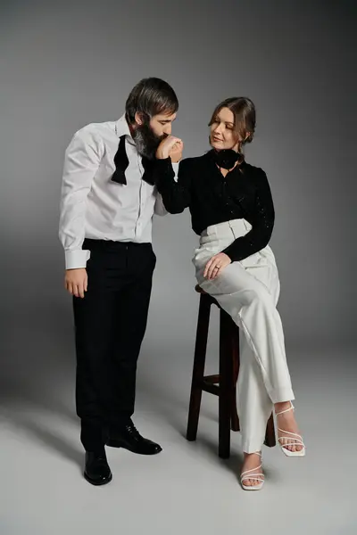 A couple in elegant attire poses together against a grey backdrop. — Stock Photo