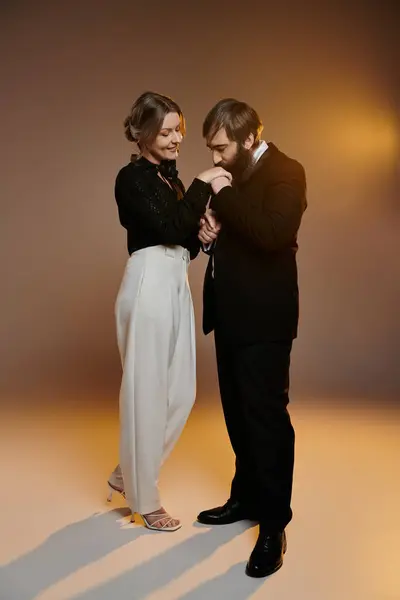 Una coppia amorevole in abiti eleganti, l'uomo che bacia la mano delle donne mentre sorride teneramente. — Foto stock