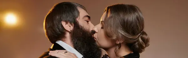 Un couple aimant, vêtu d'une tenue formelle, partage une étreinte passionnée sous une lumière chaude et dorée. — Photo de stock