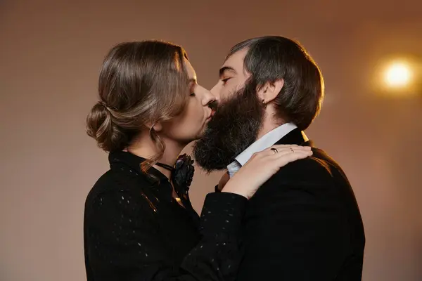 Una pareja amorosa en traje de corbata negra comparte un beso apasionado. - foto de stock