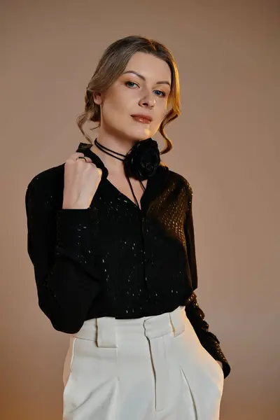 A woman in a sophisticated black blouse and white pants poses with a captivating gaze. — Stock Photo