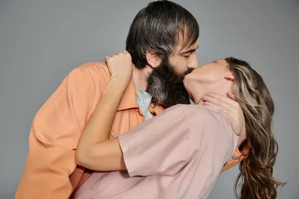 Una pareja amorosa vestida con un atuendo sofisticado abraza y besa en un ambiente de estudio. - foto de stock