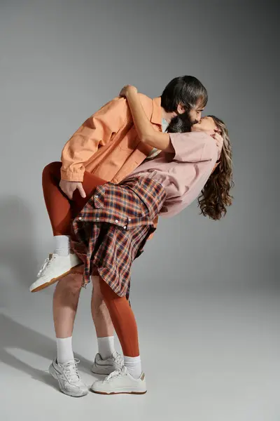 A couple in sophisticated attire embraces and kisses in a studio setting. — Stock Photo