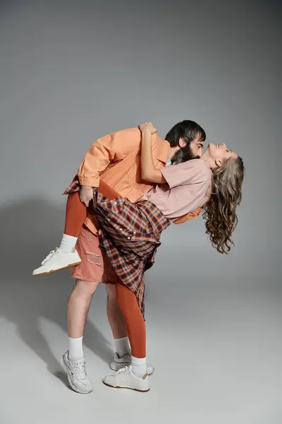A couple in stylish attire poses lovingly, the man holding the woman in his arms. — Stock Photo