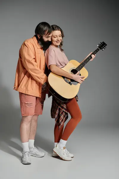 A man and woman pose together, the woman playing an acoustic guitar. — Stock Photo