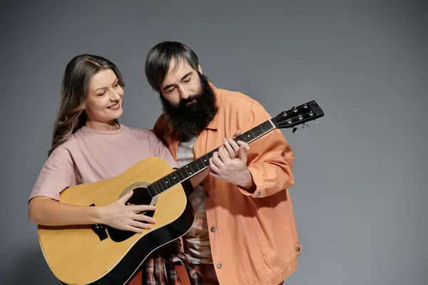 A loving couple poses together, the man playing a guitar while the woman smiles lovingly. — Stock Photo