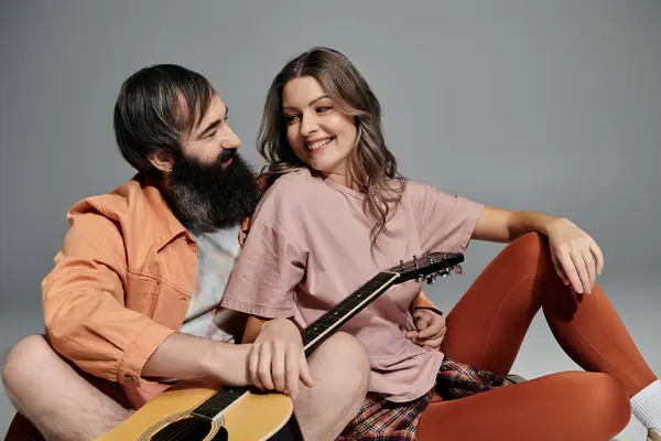 A loving couple poses together, with the man playing a guitar. — Stock Photo