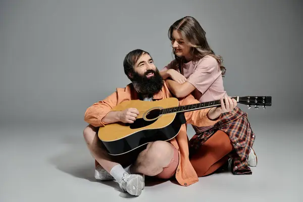 A man and woman pose together, the man playing a guitar while the woman watches him with affection. — Stock Photo