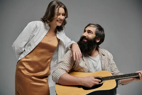 Ein Paar posiert zusammen, der Mann spielt eine Gitarre und blickt die Frau liebevoll an. — Stockfoto
