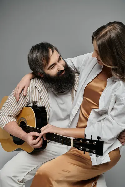 A couple in elegant attire shares a tender moment, the man playing a guitar while the woman lovingly rests her arm on his shoulder. — Stock Photo