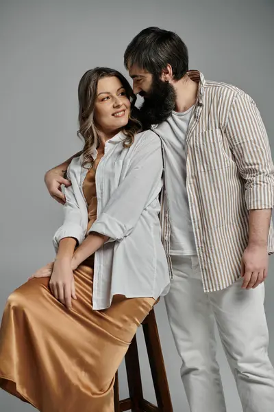Una coppia in elegante abbigliamento, la donna seduta su uno sgabello, guarda il suo partner con affetto. — Foto stock