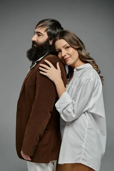Una coppia amorevole posa insieme in un elegante abbigliamento su uno sfondo grigio. — Foto stock