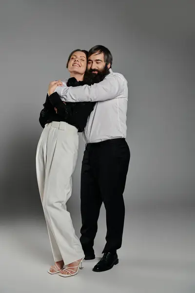 A loving couple dressed in elegant attire embraces each other in a studio setting. — Stock Photo