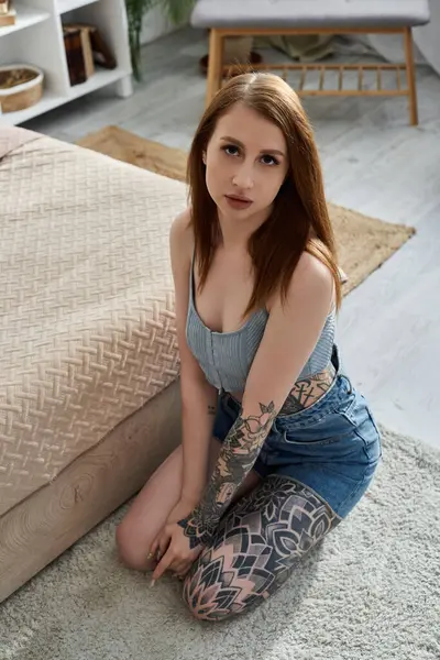 Eine junge Frau mit Tätowierungen sitzt auf dem Boden ihrer modernen Wohnung und genießt ein gemütliches Wochenende. — Stockfoto