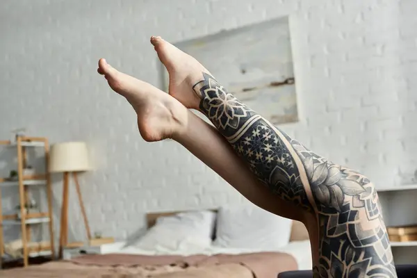 A close-up of a tattooed womans leg resting on a bed in a modern apartment. — Stock Photo