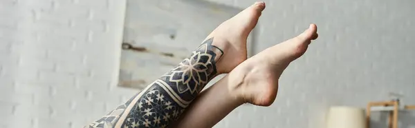 A womans feet with a detailed tattoo are resting on a couch in a modern apartment. — Stock Photo