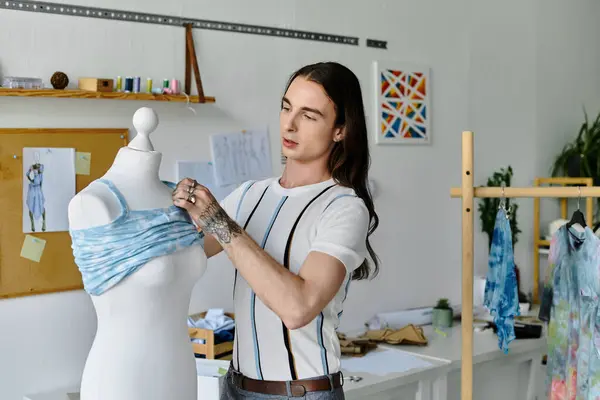 A young man meticulously adjusts a blue garment on a mannequin in his DIY clothing restoration atelier. — Stock Photo