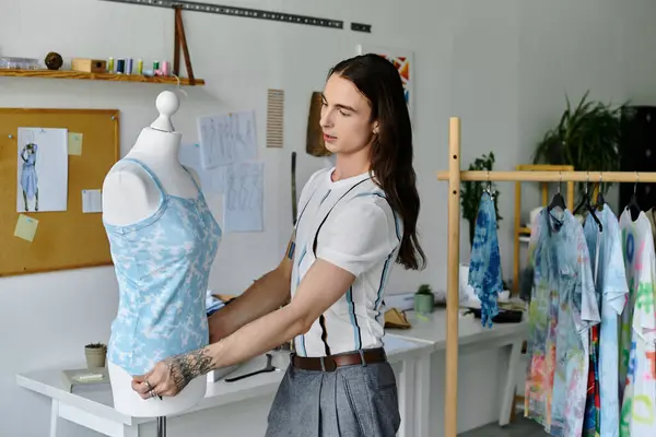 A young man adjusts a garment on a dress form in his DIY clothing restoration atelier. — Stock Photo