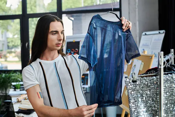 A young man examines a piece of clothing he is restoring in his DIY atelier. — Stock Photo