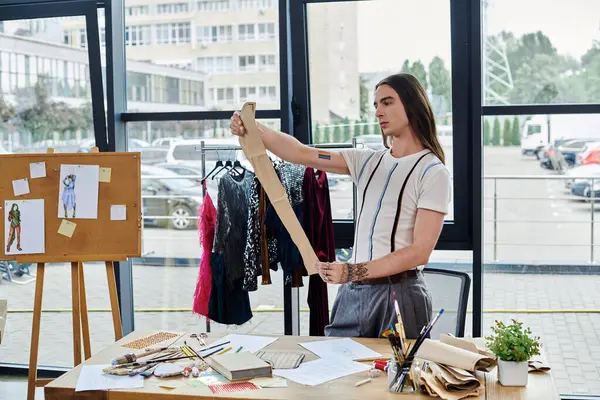A young man measures fabric in his clothing restoration atelier, showcasing his passion for sustainability. — Stock Photo