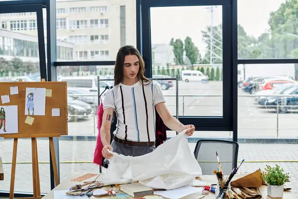 A young man meticulously examines a piece of fabric in his clothing restoration atelier, showcasing his dedication to sustainability and giving new life to old items. — Stock Photo