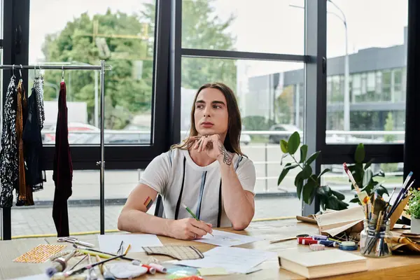A young man works on a design project in his clothing restoration atelier. He is focused on sustainability, giving new life to old items. — Stock Photo