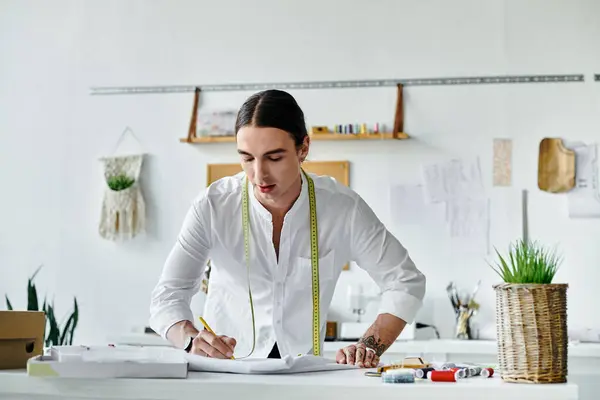 A young man, wearing a white shirt, is working in his atelier, focusing on reviving old clothes and giving them a new life. — Stock Photo